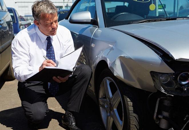 an auto insurance policy document being signed at an office desk